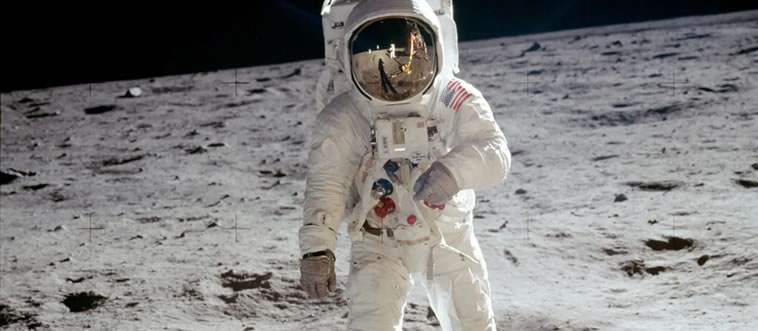 A figure in a suit plants a flag on a dusty, cratered void.